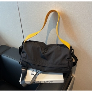Detail of black sports duffel bag with a vibrant yellow handle and dual zipper closure