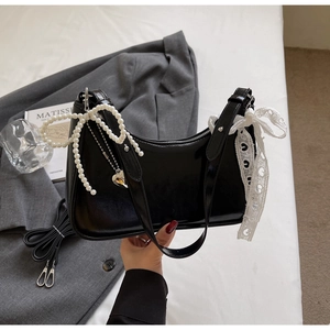 Dettaglio borsa hobo nera lucida con fiocco di perle, pizzo e ciondolo a cuore argento