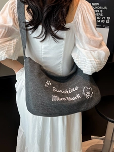 Sac bandoulière gris foncé grande capacité avec broderie blanche porté par un modèle