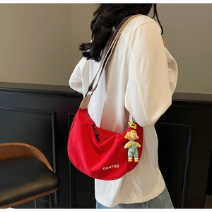 Red dumpling cross-body bag with wide striped strap and a cute cartoon charm