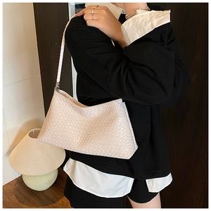 Détail d'un sac hobo tressé crème montrant la texture délicate et la bandoulière