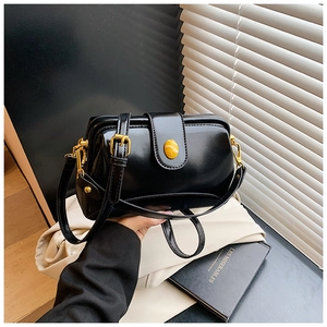 Détail du sac bandoulière en cuir verni noir avec boucle dorée et pierre ambrée