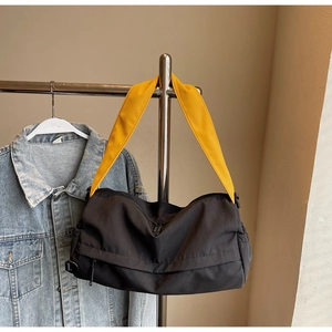 Detail of black nylon crossbody bag featuring a vibrant wide yellow shoulder strap