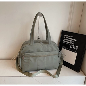Detail of quilted sage green nylon travel bag featuring side pockets and zip pocket