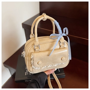 Detail of beige wrinkled leather handbag with lace trim and blue checkered ribbon