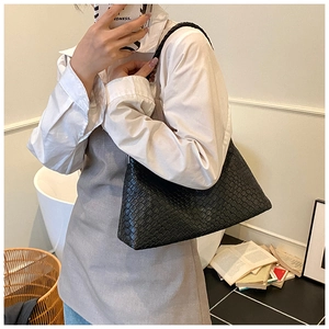 Détail d'un sac hobo en cuir tressé noir avec un design minimaliste porté à l'épaule