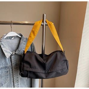 Detail of black sporty pillow bag with contrast yellow strap hanging on a metal hanger