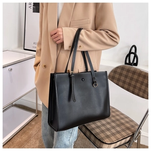 Close-up of black leather tote bag with contrast white stitching and metal ring detail