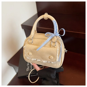 Detail of beige Boston bag with delicate lace trim and blue checkered bow ribbon