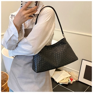 Détail du sac à bandoulière noir effet crocodile avec bandoulière tressée sur modèle