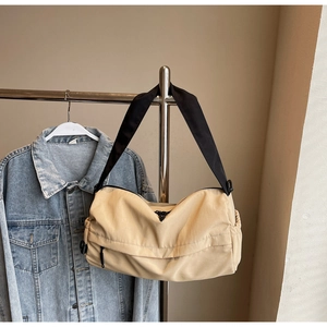 Close-up of beige nylon pillow bag with black wide strap and triangle logo detail