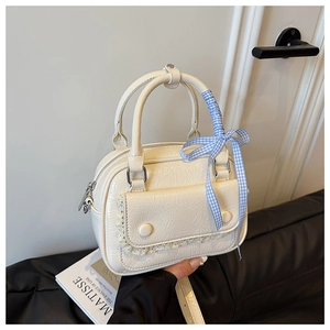 Detail of white pleated leather handbag featuring lace trim and blue checkered silk ribbon