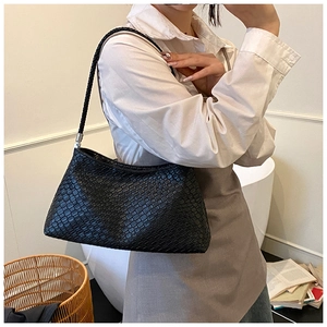 Détail du sac à bandoulière noir tissé avec boucle argentée et lanière tressée sur le modèle