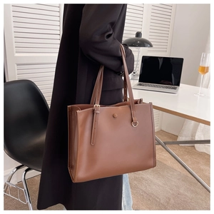 Detail of a brown leather tote bag with white contrast stitching for office attire