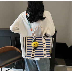 Blue and white striped canvas tote bag detail with yellow smiley face and woven strap