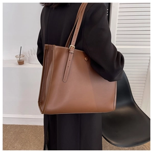 Detail of brown tote bag with white contrast stitching and adjustable gold buckle strap