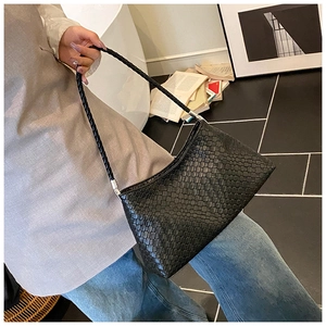 Détail du sac porté épaule tressé noir montrant la texture complexe sur un mannequin