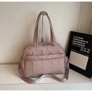 Detail of pink travel bag with quilted front pocket, metal zippers and wide shoulder strap