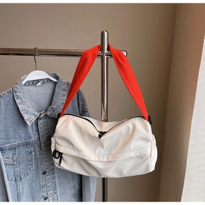 Detail of a sporty crossbody bag showing the orange strap and black metal D pendant
