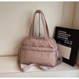 Close-up of pink nylon travel tote bag featuring multiple pockets and quilted details