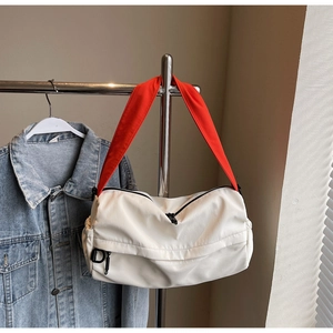 White nylon shoulder bag with orange strap shown against a denim jacket background