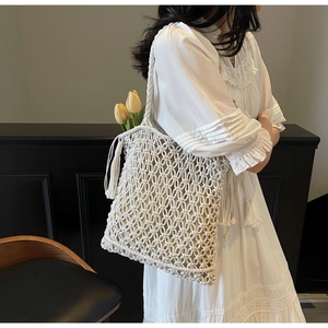 Détail d'un sac cabas tissé main blanc cassé avec pampilles et texture en maille ajourée