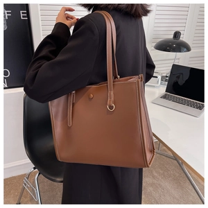 Detailed view of brown tote bag featuring white contrast stitching and long shoulder straps