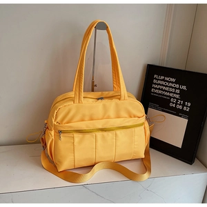 Detailed close-up of yellow nylon travel bag showing vertical quilting and multiple pockets