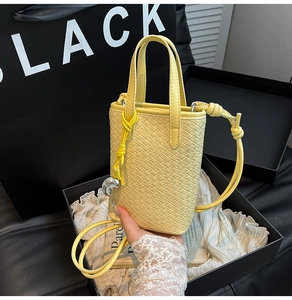 Dettaglio della mini borsa tote gialla in pelle intrecciata con ciondolo a cuore