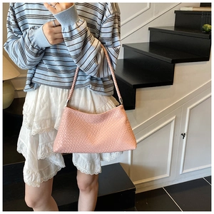 Détail de la texture tissée rose et de la bandoulière tressée du sac à bandoulière chic