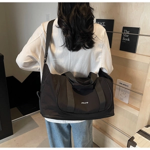 Détail du grand sac de sport noir avec imprimé NO CO porté par un mannequin en situation