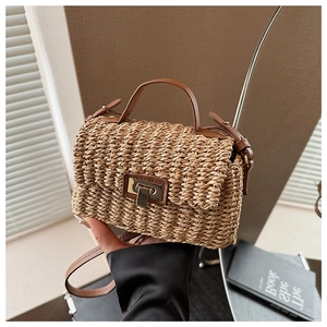 Close-up of woven straw handbag with brown leather handles and vintage metal twist lock