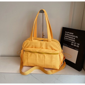 Close-up of a yellow quilted travel tote with adjustable strap and side drawstring pockets