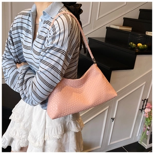 Détail d'un sac sous le bras en similicuir rose avec texture gaufrée sur un mannequin