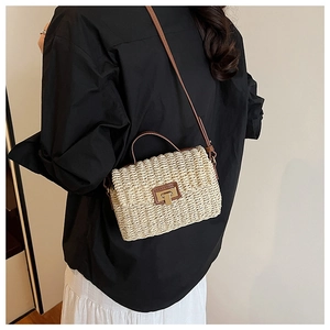 Detail view of woven straw crossbody bag with brown leather strap on female model