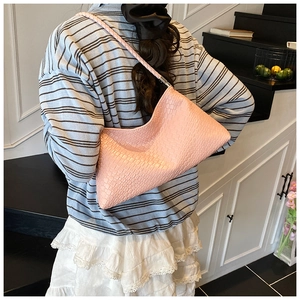 Détail du sac hobo rose avec texture crocodile et bandoulière tressée élégante