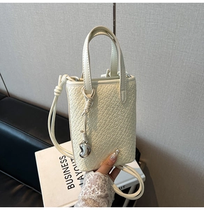 Dettaglio della borsa tote bianco crema effetto coccodrillo con ciondolo in metallo e tracolla
