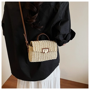 Detail view of woven straw crossbody bag with brown PU straps and gold buckle closure