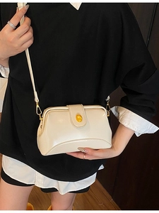 Sac à main beige style docteur avec fermoir doré vintage porté sur une tenue chic