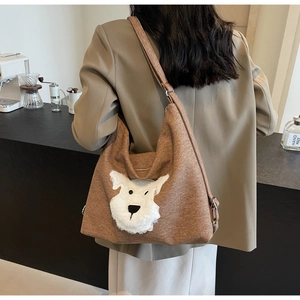 Brown canvas hobo bag with 3D plush puppy decor shown in a modern cafe setting