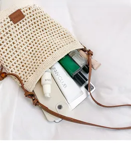 Vue détaillée d'un sac cabas en crochet crème avec cosmétiques et lanières en cuir