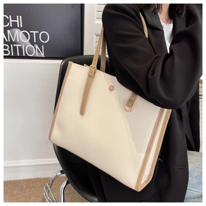 Detail of a large ivory tote bag with khaki trim and long strap worn on shoulder