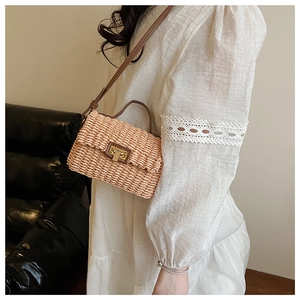 Close-up of woven crossbody bag featuring brown leather trim and golden twist lock