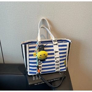 Blue and white striped canvas tote bag detail with yellow smiley face and floral charms