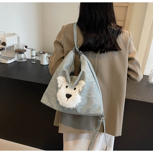 Detail of grey textured tote bag featuring a plush schnauzer dog patch in a cozy cafe