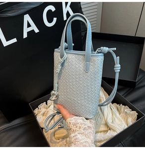 Dettaglio mini borsa tote in pelle intrecciata azzurra con ciondolo a cuore e confezione