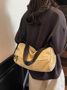 Fashionable beige cylinder shoulder bag with adjustable black strap shown on model
