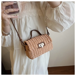 Detail of hand-woven straw crossbody bag with brown leather strap and metal turn-lock