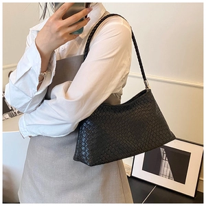 Détail du sac à bandoulière tressé noir montrant sa texture et son design minimaliste