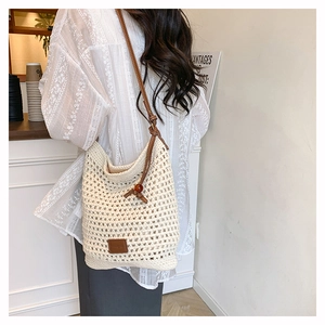 Détail d'un sac cabas tissé crème avec des lanières en cuir marron dans un café chic